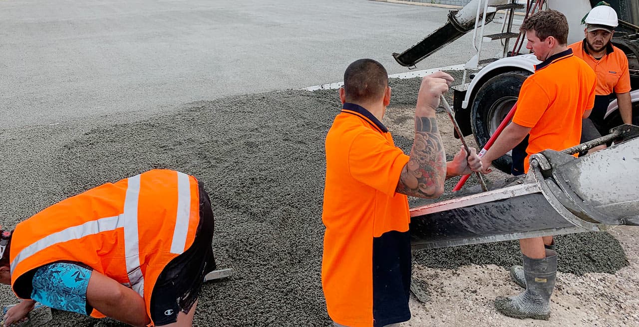 Workers levelling fresh permeable concrete at the chute during a commercial pour