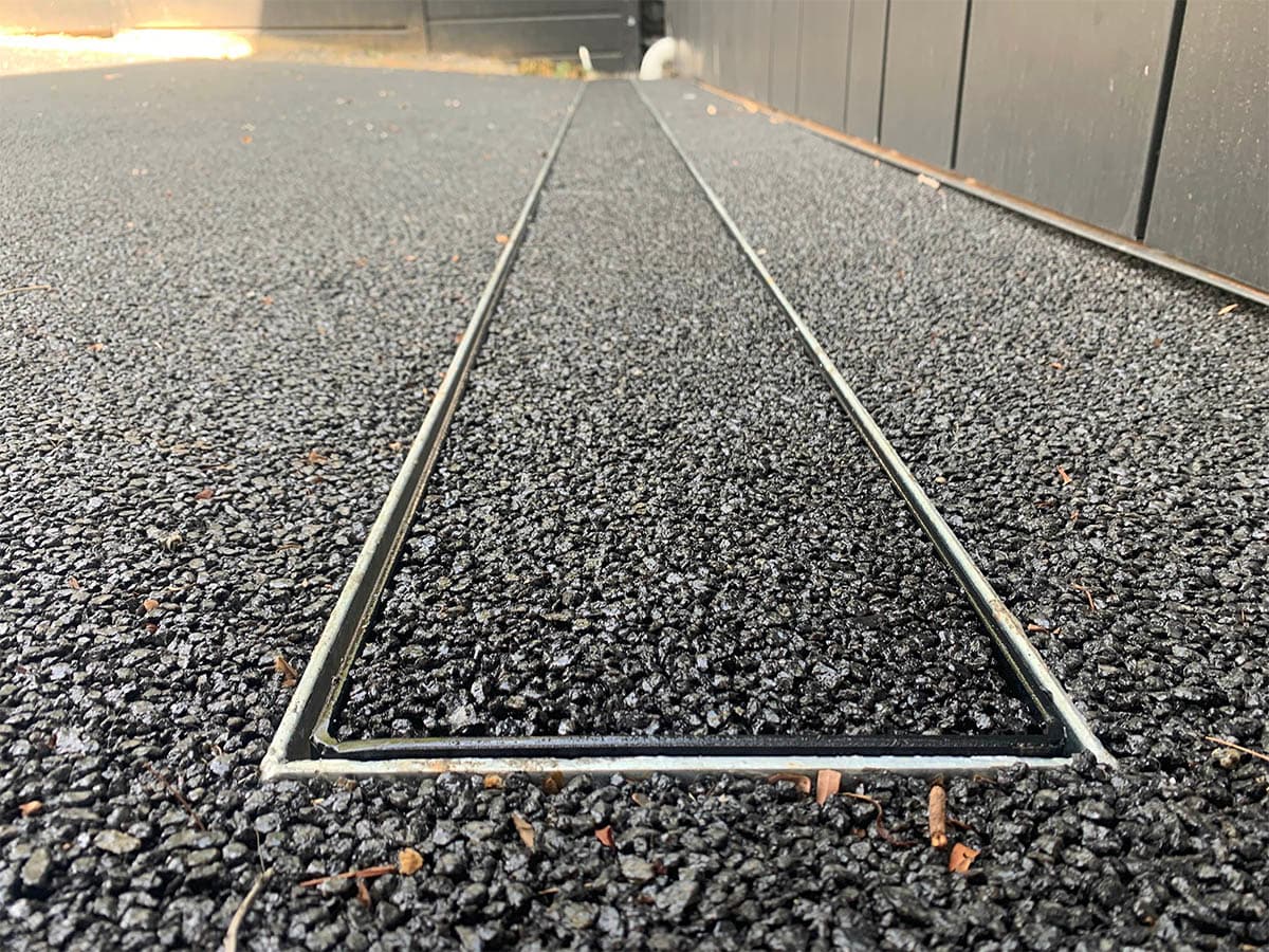 A newly poured permeable concrete footpath beside a suburban street with a smooth exposed-aggregate finish.