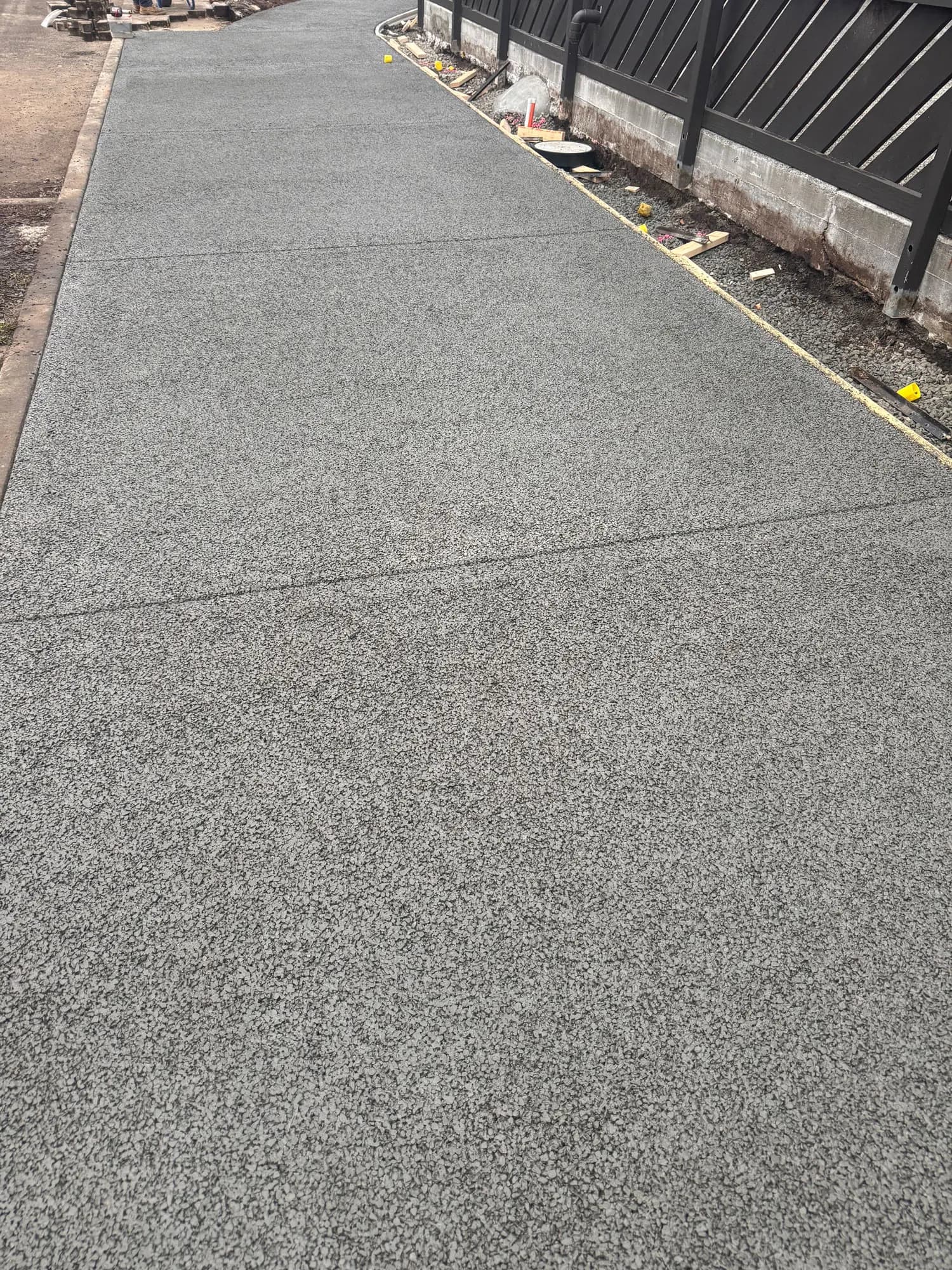 Hobart footpath resurfaced in permeable concrete, showing an even, textured grey finish along the kerb line.