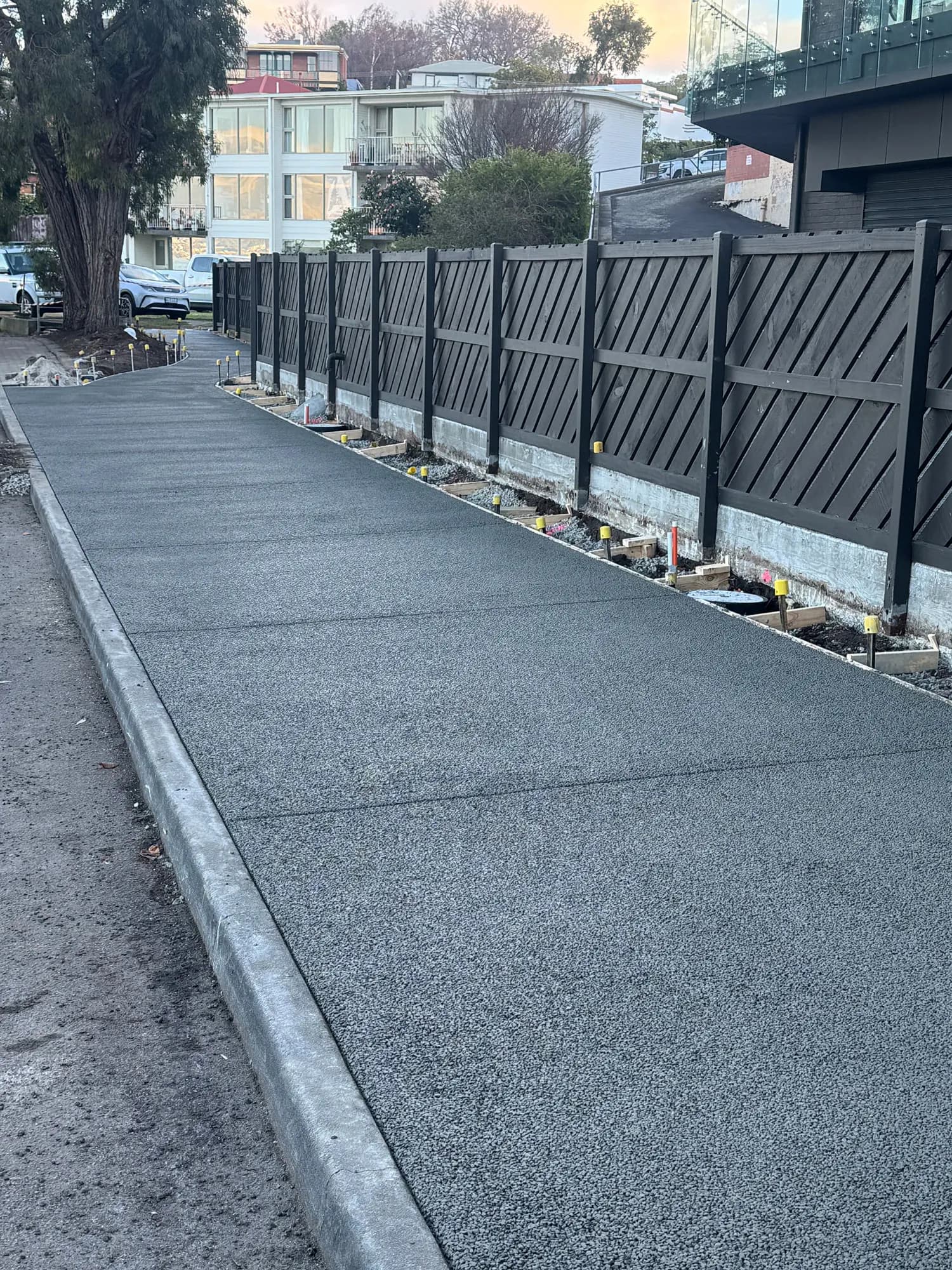 Completed permeable concrete footpath in Hobart with an even, exposed-aggregate finish beside kerb and garden edge.