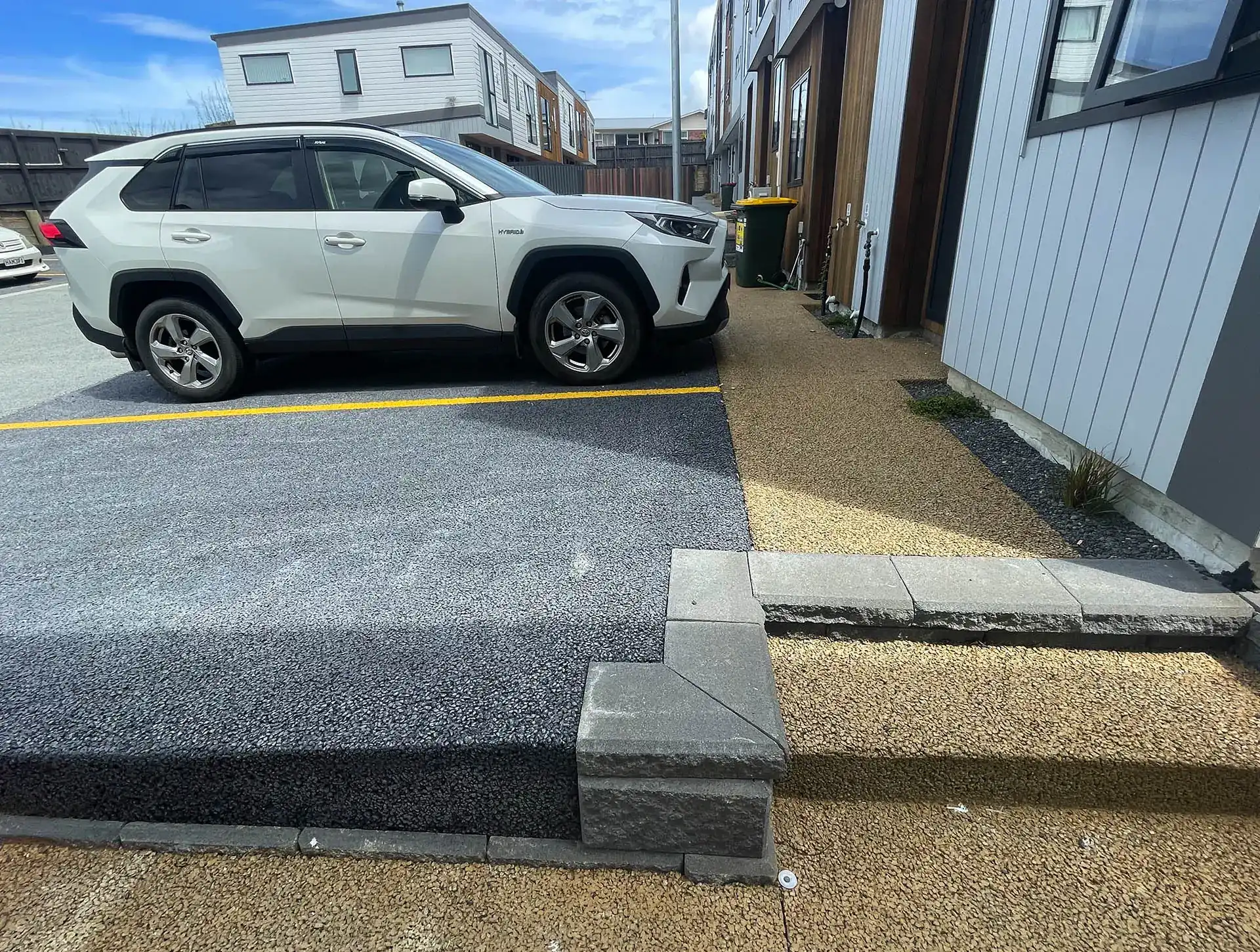 SUV parked on a permeable concrete driveway strip outside a townhouse